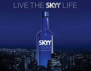 一個巨大的藍色Skyy伏特加酒瓶矗立在夜晚燈火通明的城市之上。