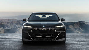 黑色BMW i7電動轎車停在懸崖上，俯瞰黎明的山脈。