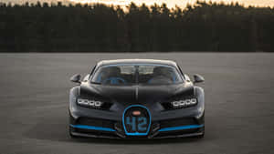 日落時分賽道上的黑色Bugatti Chiron，帶有藍色飾邊。 — 布加迪 壁紙
