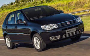 黑色Fiat Palio Fire在陽光明媚的高速公路上行駛，背景是綠色山丘。 — Steam Deck OLED 壁紙