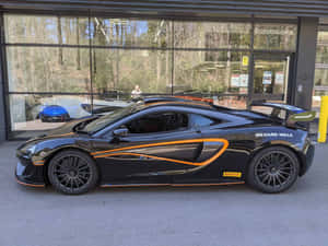 黑色McLaren跑車帶有橙色條紋停在經銷商外。 — 4K 法拉利 壁紙