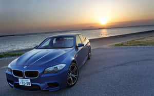 日落時藍色BMW M5停在水邊 — MacBook Air M1 壁紙
