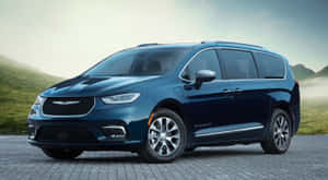 藍色 Chrysler 小型貨車停泊在石路上，靠近霧氣瀰漫的山丘。