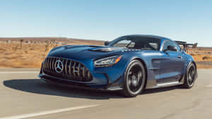 藍色 Mercedes-AMG GT R 在日落時分於沙漠高速公路上飛馳。 — 平治 AMG 壁紙