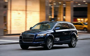 深藍色Audi Q7 TDI SUV夜間在城市街道上行駛。 — Steam Deck 壁紙