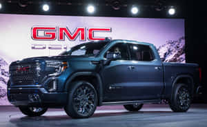 深藍色 GMC Sierra Denali 皮卡車在舞台上，背景為山脈。 — Steam Deck OLED 壁紙
