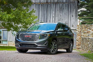 深綠色GMC Acadia SUV停泊在木製穀倉和石牆附近。 — Surface Pro 壁紙