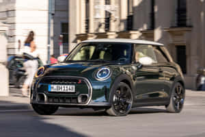 深綠色MINI Cooper S配白色車頂在日落時分行駛在城市街道上。 — Surface Pro 壁紙
