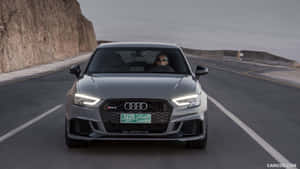 灰色Audi RS3在黃昏時分行駛在海岸公路上，有海洋和懸崖。 — 奧迪 GIF 壁紙
