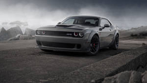 灰色 Dodge Challenger SRT Hellcat 在風暴中的海岸公路上，海浪拍打和混凝土屏障。