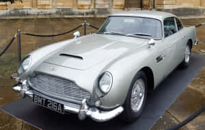 銀色經典Aston Martin DB5展示，帶有繩索和石建築背景。 — Steam Deck 壁紙