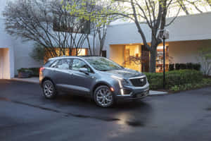 銀色Cadillac SUV在黃昏時停泊在現代房屋前。 — Surface Pro 壁紙