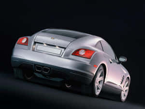 銀色 Chrysler Crossfire 跑車從後方四分之三角度在深色工作室中觀看。 — OLED 壁紙