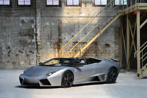 銀色林寶堅尼 Reventon Roadster 在一個有黃色金屬樓梯的工業倉庫內。 — Surface Pro 壁紙