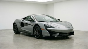 極簡工作室中的銀色McLaren跑車，混凝土地板。