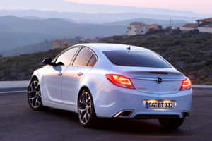 銀色Opel Insignia GTC停泊在日落時分的風景優美沿海公路上。 — Oppo 壁紙