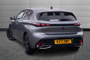 銀色Peugeot 308掀背車停在行人路上，灰色牆壁背景。 — Surface Pro 壁紙