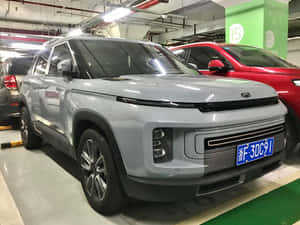 銀色SUV停放在地下停車場，旁邊有一輛紅色汽車。 — 酷車 壁紙