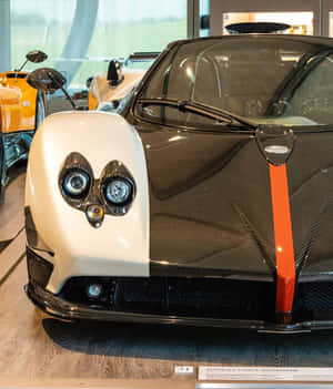 白色和碳纖維帕加尼Zonda Cinque Roadster，帶有橙色條紋，在展廳中。 — Motorola Razr Ultra 2025 壁紙