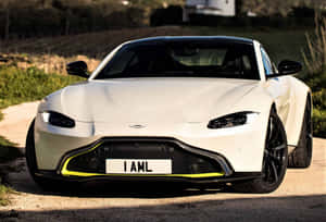 白色Aston Martin跑車，黃色飾邊，停泊在碎石小徑上。 — Surface Pro 壁紙