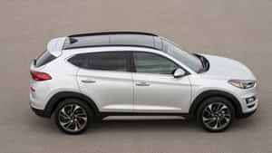 白色現代 Tucson SUV 從上方俯瞰停在灰色瀝青上。 — 現代汽車 壁紙