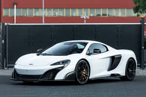 帶有黑色細節的白色McLaren跑車停在紅樓附近的人行道上。 — Surface Pro 壁紙