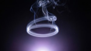 一個發光的白色煙圈漂浮在黑暗空間中，下方有紫色光