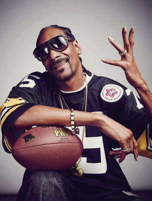 Snoop Dogg 身穿美式足球球衣，手持足球並揮手。