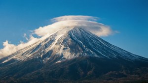在清澈的藍天下，白雪覆蓋的富士山頂上有透鏡狀雲。