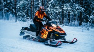 人在雪地森林中駕駛火焰設計的雪地摩托車