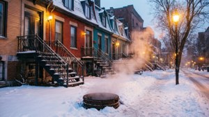白雪覆蓋的街道，蒸氣從桶中升起，靠近被街燈照亮的色彩繽紛聯排別墅。