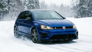 一輛藍色福士Golf在雪路上行駛，穿過冬季森林。