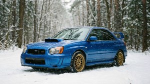 藍色Subaru WRX STI配金色輪圈停泊在積雪森林中，正值下雪