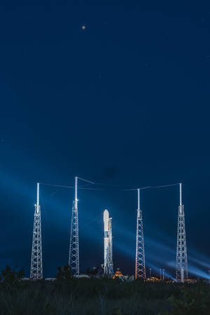 一枚火箭在發射台上，在星光夜空下被聚光燈照亮。 — Spacex GIF 壁紙