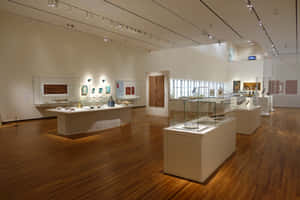 現代博物館畫廊，木地板和玻璃展示櫃內有古代文物。 — Surface Pro 壁紙