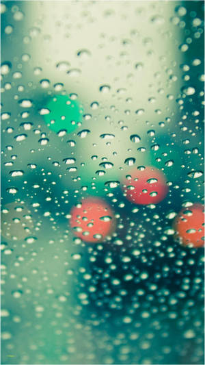 玻璃上的雨滴，模糊的城市燈光閃爍著紅色和綠色。