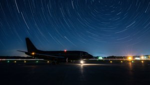 黑暗的飛機在跑道上，星空下帶有光跡