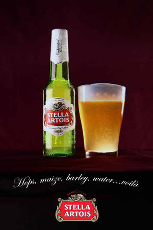 Stella Artois啤酒瓶和玻璃杯放在天鵝絨上，帶有品牌標誌和標語。
