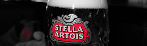 在黑暗環境中，帶有紅色標誌和泡沫頂部的Stella Artois啤酒杯。