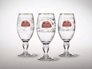三隻 Stella Artois 啤酒杯，帶有金色邊緣和蝕刻圖案，白色背景。