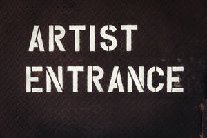 深色金屬紋理上白色模板的 artist entrance 標誌。