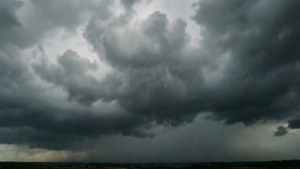 在灰色天空下，黑暗的風暴雲在平坦的地平線上下雨。
