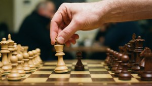 在木製棋盤上下棋時，一隻手拿起一個國際象棋兵。