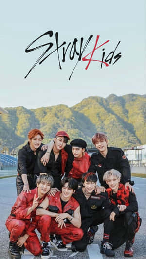 Stray Kids K-pop 組合在賽車道上擺姿勢，背後有山脈。