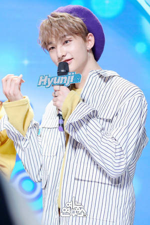K-pop表演者在舞台上微笑著拿著麥克風。