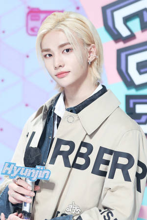 K-pop藝人Hyunjin身穿米色Burberry外套在活動中手持麥克風。