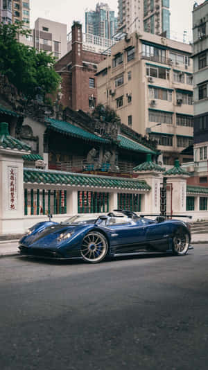 藍色跑車停泊在密集城市環境中的傳統中式寺廟旁邊。 — 精細 壁紙