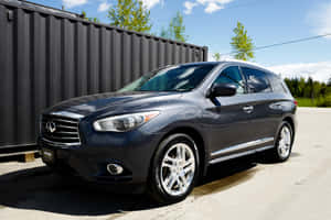陽光明媚的日子裡，深灰色 Infiniti QX60 SUV 停在黑色貨櫃附近。 — MacBook Air M4 壁紙