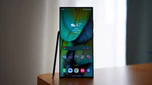 智能手機在木桌上顯示羽毛壁紙，觸控筆在旁。 — Samsung S23 Ultra 壁紙