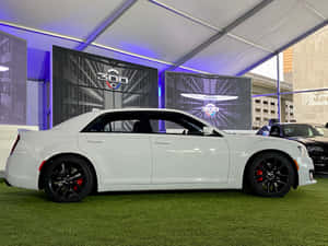 白色Chrysler 300轎車在綠色草坪上，位於照明帳篷下，帶有數字屏幕。 — 奧迪 GIF 壁紙